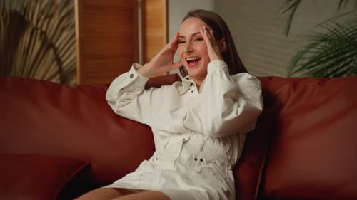 Woman Laughing on Couch in Bright Indoor Setting