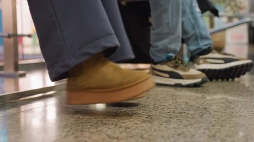 Legs of Seated People with One Person Swinging Feet in Brown Suede Shoes