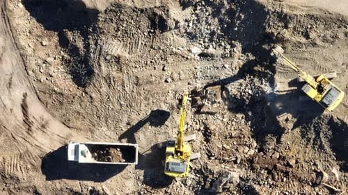 Industrial Mine Excavators are Digging the Soil in the Construction Site and Loading Trucks