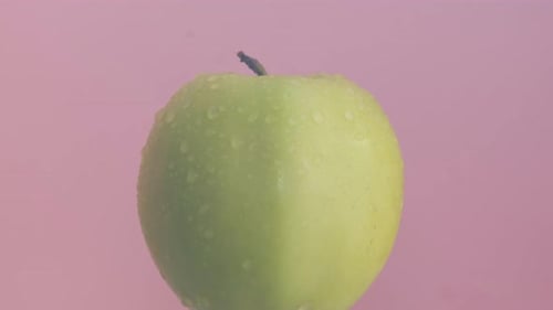 Ripe Green Apple with Water Drops Isolated on Pink Background
