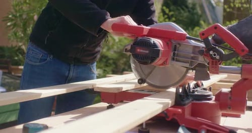 Man Cuts Lumber with Power Saw Outdoors
