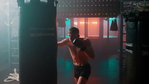 Intense Man Boxing Heavy Bag in Gym
