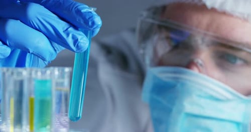 In a laboratory, a scientist with a pipette analyzes a colored liquid to extract the DNA and molec