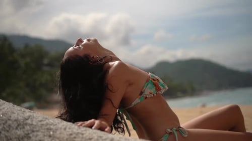 Sexy young woman relaxing on the beach wearing a bikini - slow motion