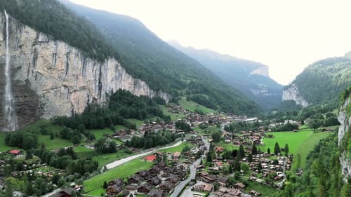 Aerial reveal of the Lauterbunnen in Grindelwald Switzerland, showing the cityscape and waterfall