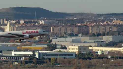 Avião Lauda voando contra a paisagem urbana de Madrid com área industrial