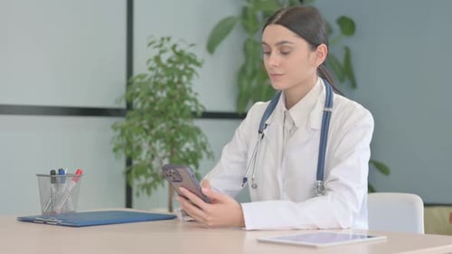 Young Female Doctor Using Smartphone in Clinic