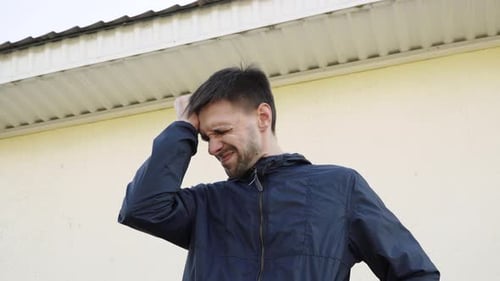 Portrait of Upset Man in Depressed State Hitting Himself on Head with His Hand