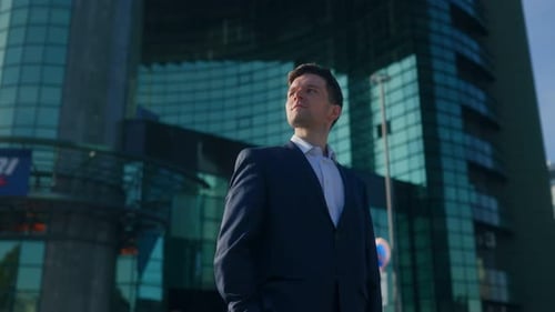 Confident Young Man in Suit Standing in City with Modern Buildings