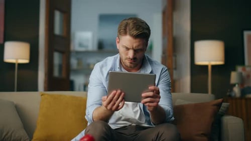 Man Using Tablet Relaxing on Sofa Indoors