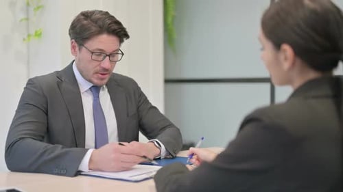 Geschäftsmann im Gespräch mit junger Geschäftsfrau, Kollegen bei der Arbeit