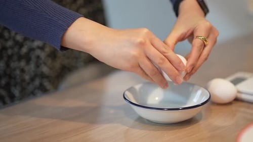 Die Hand einer Frau zerbricht ein Ei