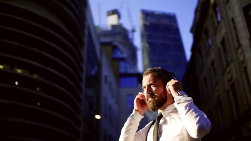 Hipster-Geschäftsmann mit Kopfhörern steht auf der Straße in London in The