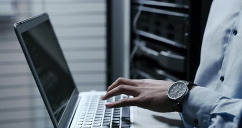 Man Coding on Laptop in Server Room