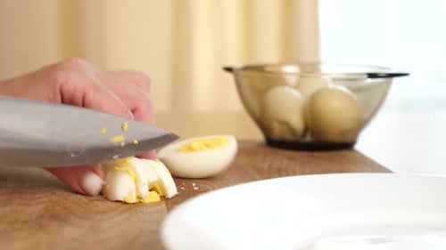 Hand Dices Hard Boiled Egg on Cutting Board