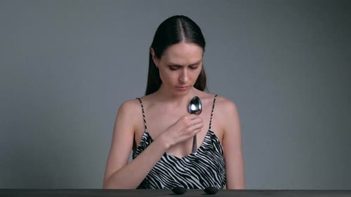 Femme magnétique avec des cuillères attachées à sa peau