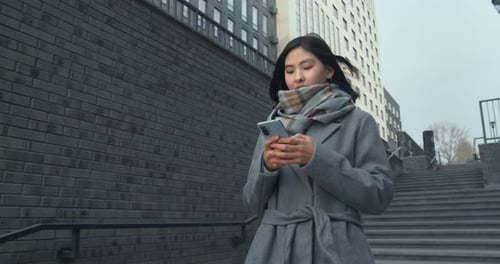 Portrait of Asian Woman Typing on Mobile Phone Outdoors