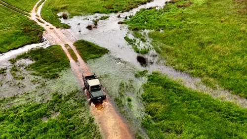 4x4 pickup reverse through flooded dirt road crossing to avoid danger, aerial