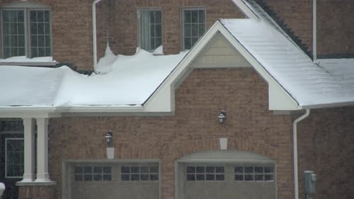 Close up of Snowstorm with snowflakes falling onto basic generic 2-story brown brick house with whit