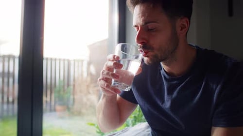 Man Drinks Water Indoors in a Home Setting