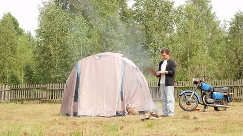 Man Camping with Tent, Motorcycle, and Tablet