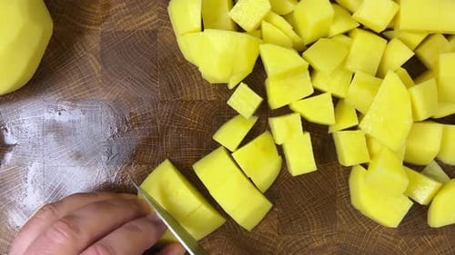 Cutting Fresh Potatoes on Wood Board for Cooking