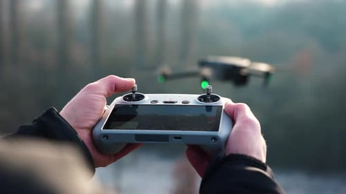 Hands Operating a Drone in a Forest