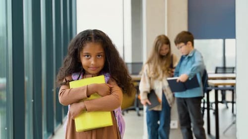 Cute Schoolgirl Holding Books in Hallway