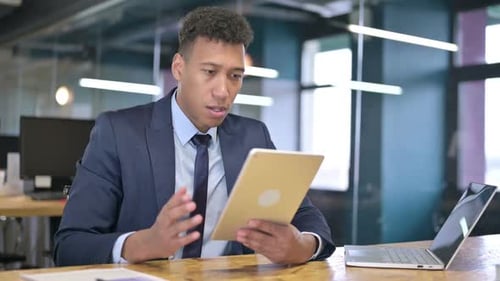 Frustrated Young Adult Businessman Using Tablet in Office