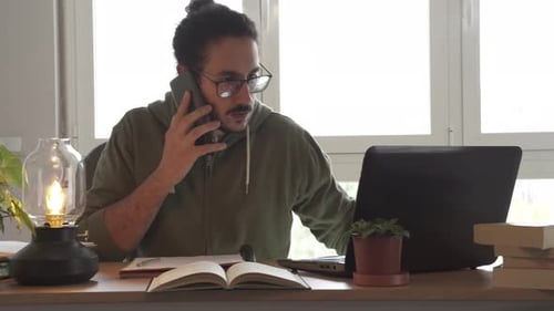 Young Adult Working at Desk and Talking on Phone