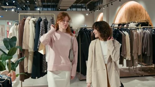 Two Cheerful Girls Putting Shopping Bags over Shoulders Walking around Store