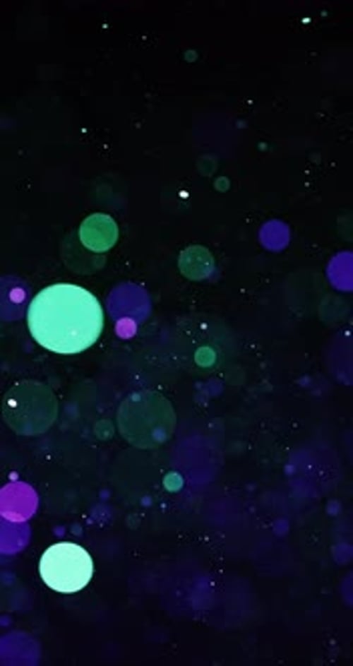Green And Violet Circular Particles Floating In The Dark