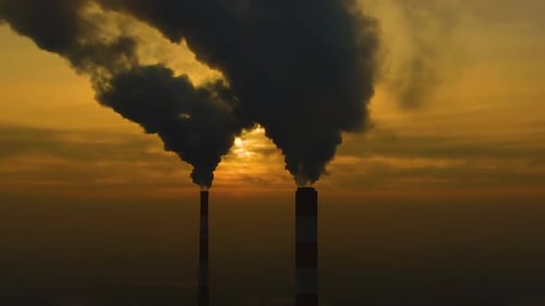 Luftverschmutzung. Rauchwolken kommen aus den Kaminen der Anlage mit wunderschönem goldgelbem Licht