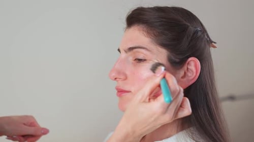 Makeup Artist's Hand Applying Foundation on Client's Face in Studio