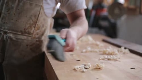 Carpenter brushing wood shavings off workbench in calgary alberta workshop
