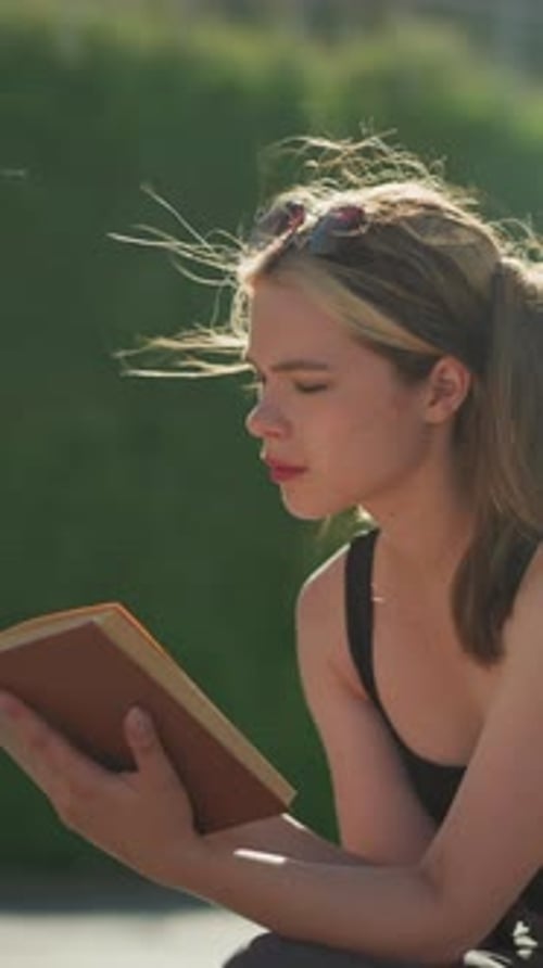 Woman Reads Book in Sunny Urban Park