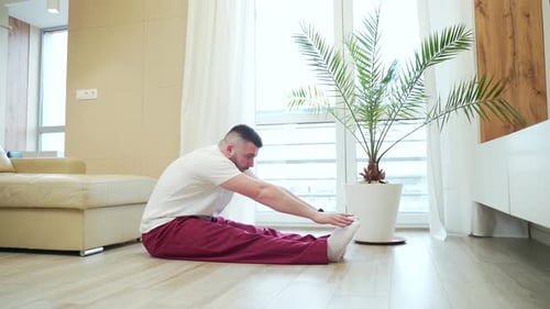 Man Sitting and Stretching in Bright Living Room