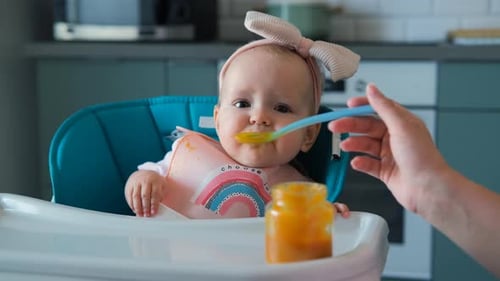 Baby Eating Food in High Chair at Home