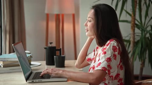 Asian Woman Working in Home Office and Typing on Keyboard of Laptop Computer