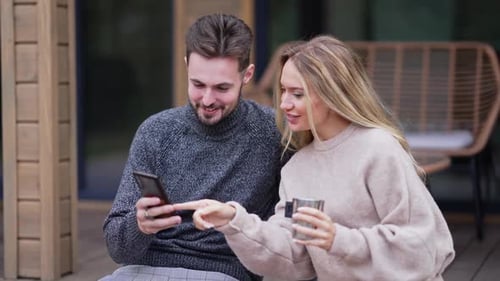 Happy Couple Looking at Phone Together Outdoors