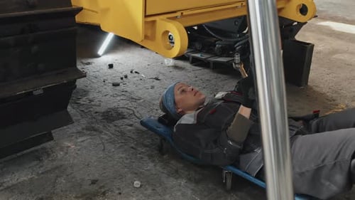 Mechanikerin arbeitet unter einer Traktormaschine