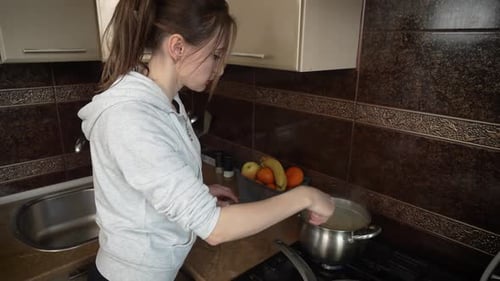 Woman Cooking in Kitchen Stirring Pot on Stove