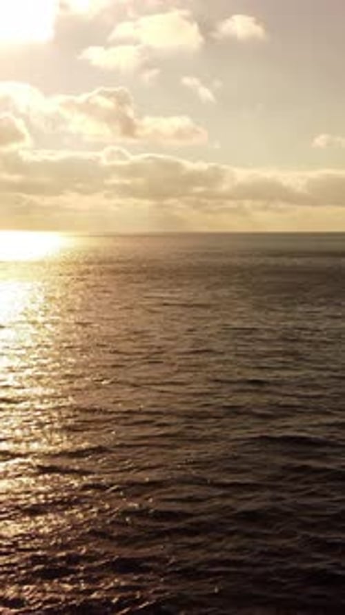 Meereswasseroberfläche bei Sonnenuntergang Vertikale Luftbildkamera fliegt über ruhigem Sonnenschein am goldenen Meer