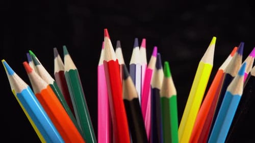 Colorful pencils rotate on black background. Rainbow pencils for drawing. Assortment of colored
