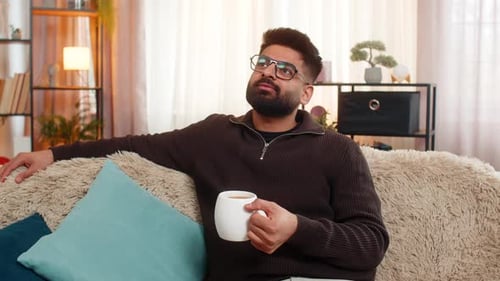 Man Relaxing on Sofa with a Mug of Coffee