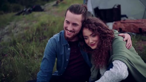Young couple resting together in a tent shelter enjoying nature's beauty