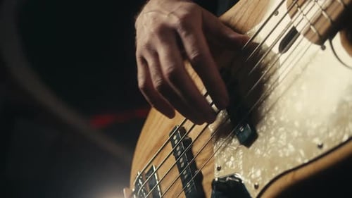 Junger Musiker sitzt und spielt elektrische Akustikgitarre inmitten von Musikgeräten im Studio
