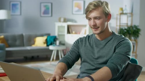 Man works on laptop in bright living room