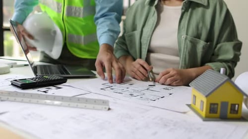 Colleague Architects Brainstorm Together To Design A Building And Drawing On Blueprints And Plan The