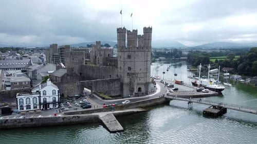 Ancient Caernarfon castle Welsh harbour town aerial view medieval waterfront landmark orbit right ab